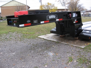 The gooseneck has a self-contained 18 HP gas engine with an independent gas tank (red container) and a tire carrier located on top (pictured without a tire).